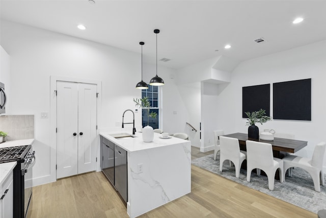 kitchen featuring appliances with stainless steel finishes, light stone countertops, light hardwood / wood-style floors, sink, and kitchen peninsula