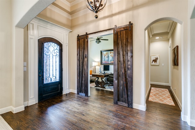 entrance foyer featuring ornamental molding, a barn door, dark hardwood / wood-style floors, and a chandelier