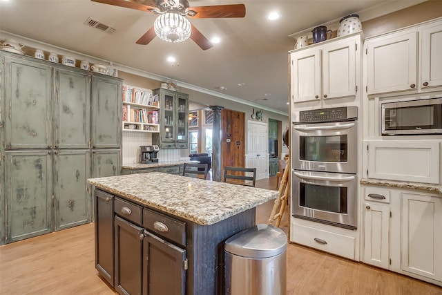 kitchen with white cabinets, appliances with stainless steel finishes, a kitchen island, and crown molding