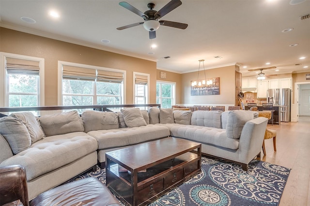 living room featuring ceiling fan with notable chandelier, light hardwood / wood-style floors, plenty of natural light, and crown molding