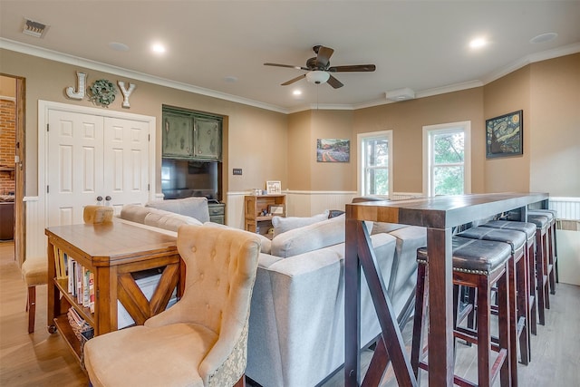 home theater featuring light hardwood / wood-style floors, ceiling fan, and ornamental molding