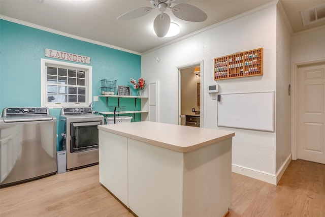 kitchen featuring ceiling fan, independent washer and dryer, light hardwood / wood-style floors, a kitchen island, and ornamental molding