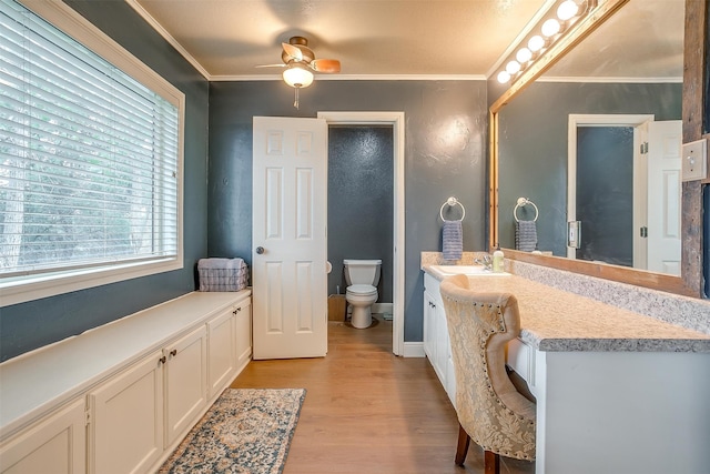 bathroom featuring vanity, ceiling fan, crown molding, wood-type flooring, and toilet