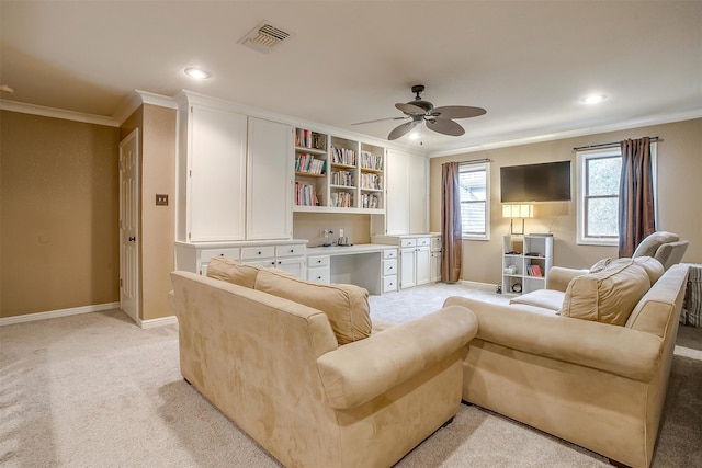 carpeted living room with ceiling fan, built in desk, and ornamental molding