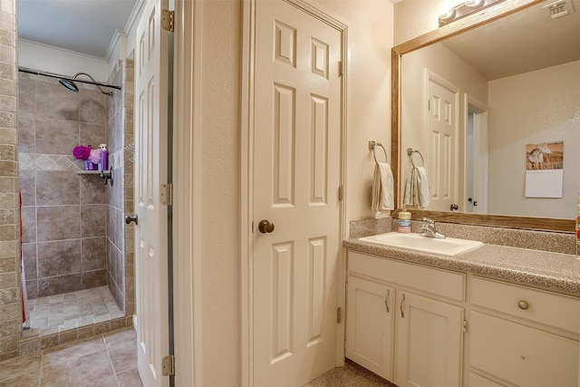 bathroom featuring vanity, a tile shower, and ornamental molding