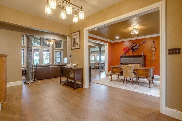 interior space with french doors, wood-type flooring, ceiling fan with notable chandelier, and ornamental molding