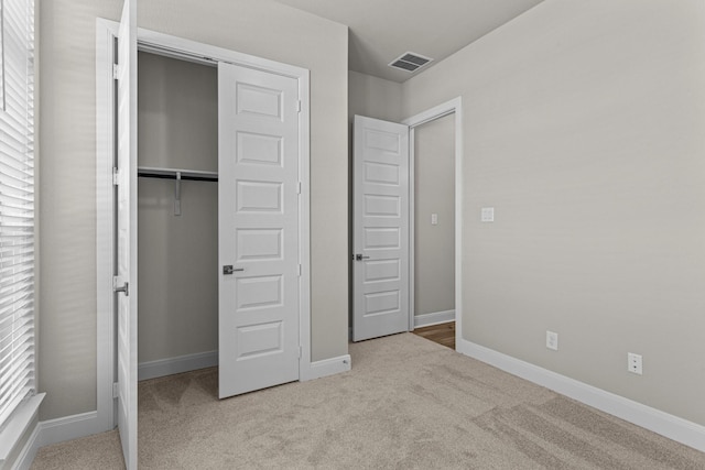 unfurnished bedroom featuring light carpet and a closet