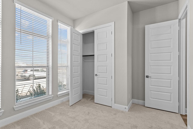 unfurnished bedroom featuring light colored carpet and a closet