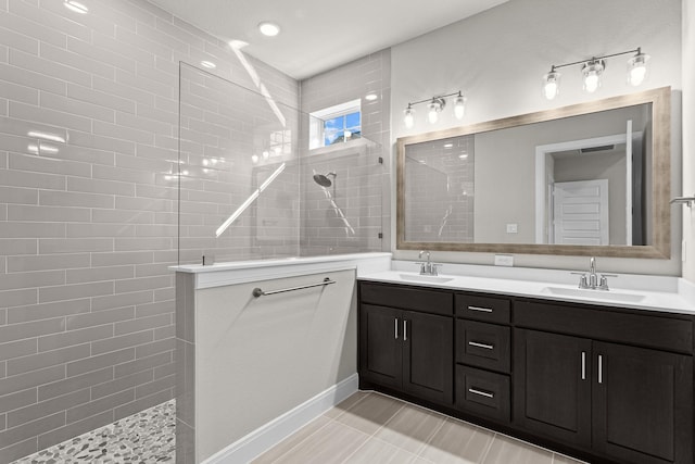 bathroom featuring a tile shower, vanity, and tile patterned flooring