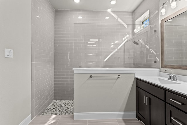 bathroom featuring vanity, tile patterned flooring, and tiled shower