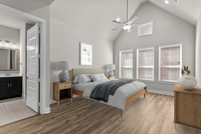 bedroom with sink, ensuite bath, ceiling fan, hardwood / wood-style floors, and vaulted ceiling