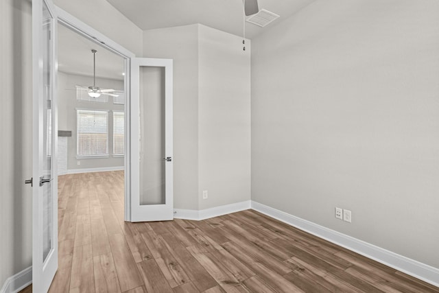 empty room featuring french doors, ceiling fan, and wood-type flooring