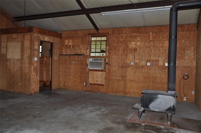 garage featuring a wall mounted air conditioner, a wood stove, and wooden walls