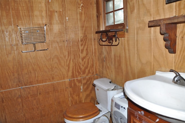 bathroom with toilet, wooden walls, washer / clothes dryer, and vanity