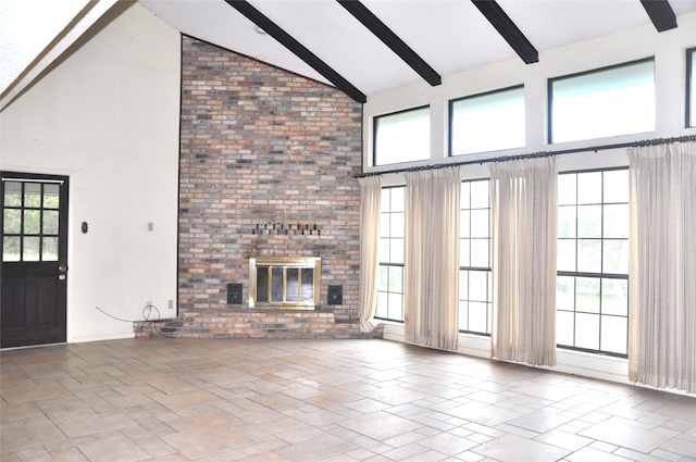 unfurnished living room featuring high vaulted ceiling, a wealth of natural light, beam ceiling, and a brick fireplace