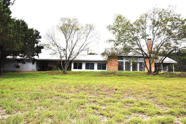 back of property featuring a chimney and a yard