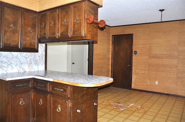 kitchen with a peninsula, dark brown cabinetry, light countertops, and a textured ceiling