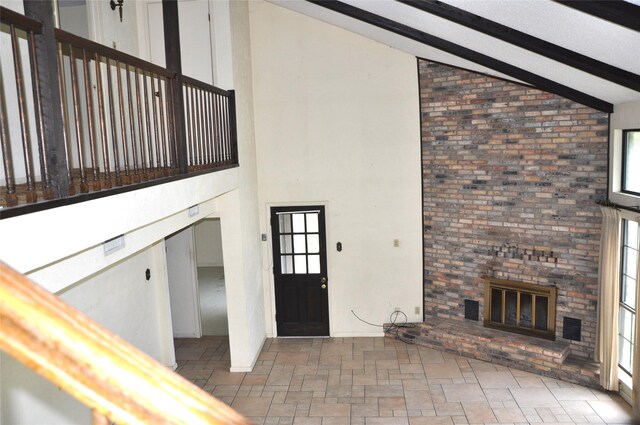 foyer with high vaulted ceiling and a brick fireplace