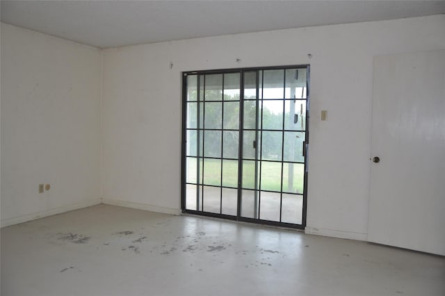 spare room featuring finished concrete floors and baseboards