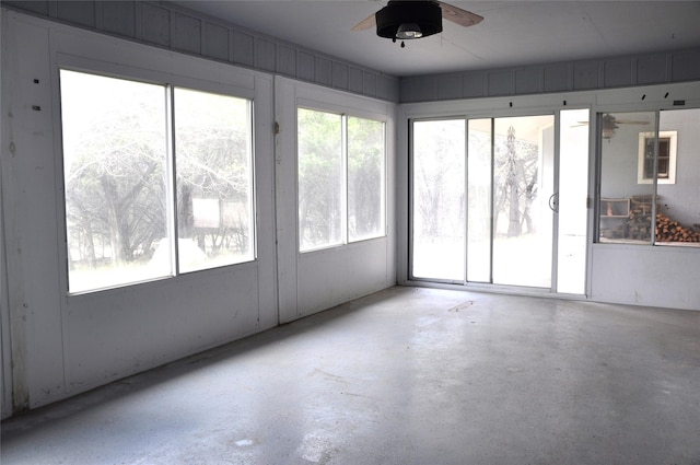 unfurnished sunroom featuring a healthy amount of sunlight and ceiling fan