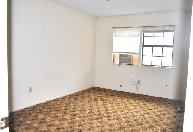 carpeted spare room featuring cooling unit and baseboards