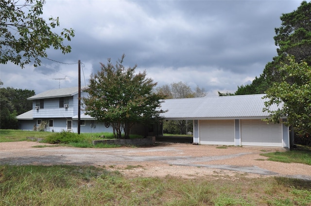 view of front of home with a carport, a garage, and dirt driveway
