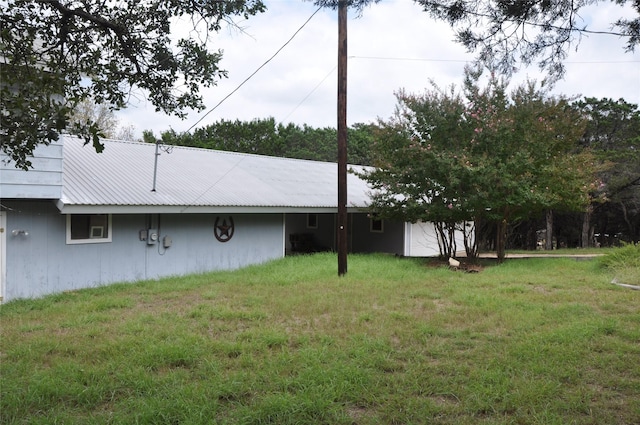 exterior space with metal roof and a yard