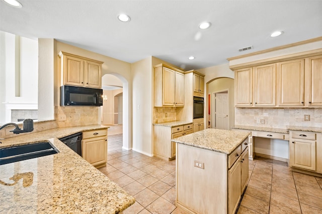 kitchen featuring light brown cabinetry, light stone counters, sink, black appliances, and a kitchen island