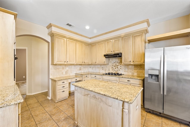 kitchen with appliances with stainless steel finishes, a center island, tasteful backsplash, and light brown cabinetry