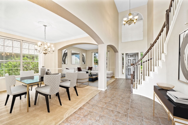 dining area featuring a wealth of natural light, a high ceiling, an inviting chandelier, and ornamental molding