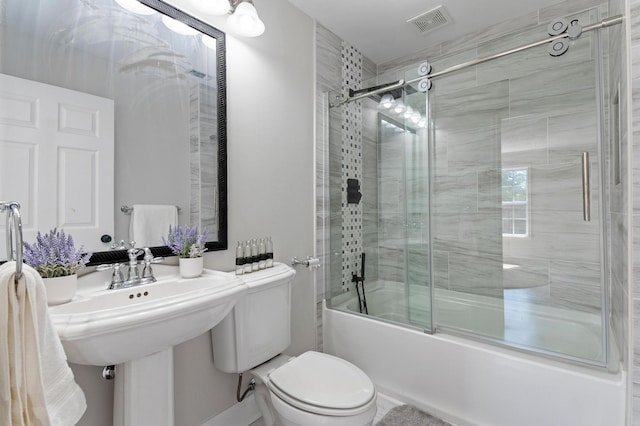 bathroom featuring toilet and bath / shower combo with glass door