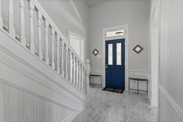 1401 Arp St, Commerce, TX 75428 - foyer entrance with wainscoting, marble look tile flooring, a towering ceiling, and a decorative wall