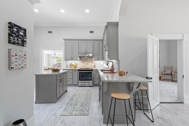 kitchen featuring a center island, gray cabinets, crown molding, and stainless steel range with electric cooktop