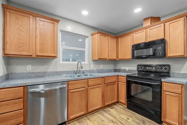 kitchen with black appliances, sink, and light hardwood / wood-style floors