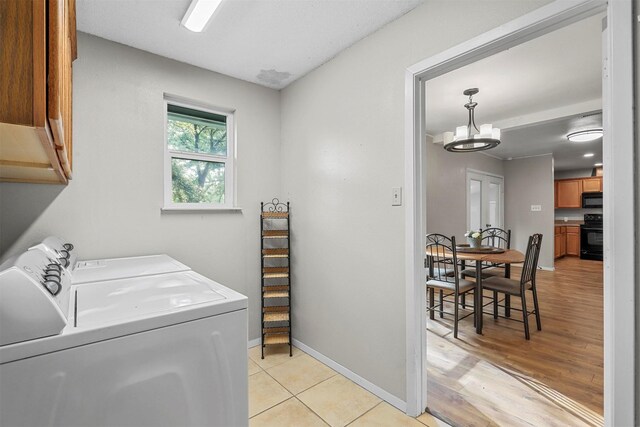 laundry room with cabinets, separate washer and dryer, light hardwood / wood-style flooring, and a notable chandelier