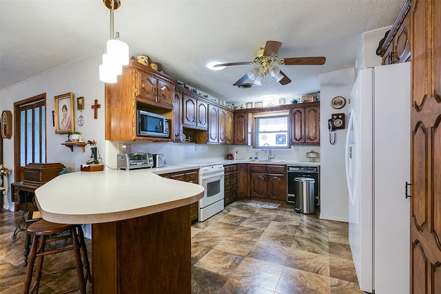 kitchen featuring white appliances, sink, ceiling fan, kitchen peninsula, and a breakfast bar area