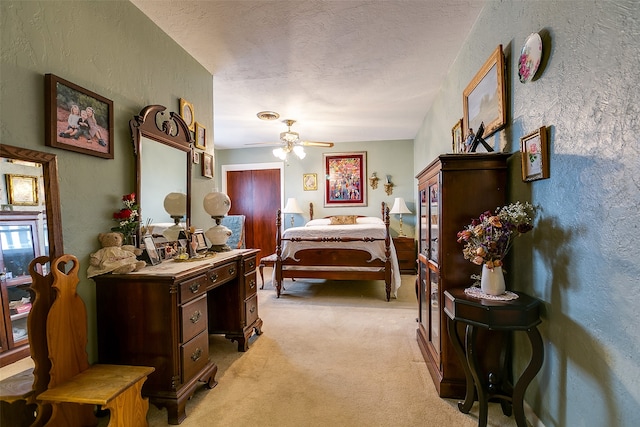 carpeted bedroom featuring ceiling fan and a textured ceiling