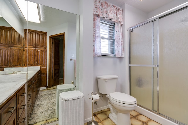 bathroom featuring an enclosed shower, a skylight, toilet, and vanity