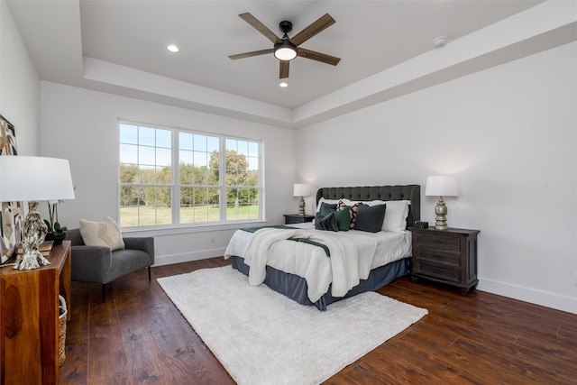 bedroom featuring dark wood-type flooring, ceiling fan, and a tray ceiling