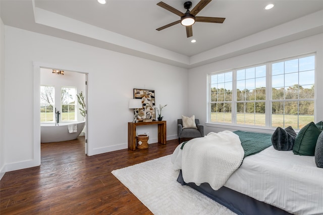 bedroom featuring a raised ceiling, dark wood-type flooring, and ceiling fan