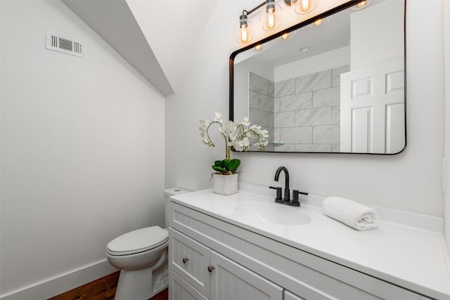 bathroom featuring hardwood / wood-style flooring, lofted ceiling, vanity, and toilet