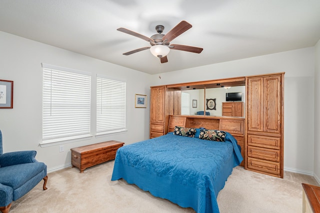 bedroom featuring light colored carpet, ceiling fan, and multiple windows