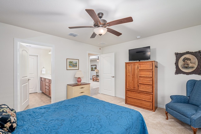 bedroom with ensuite bath, light colored carpet, and ceiling fan