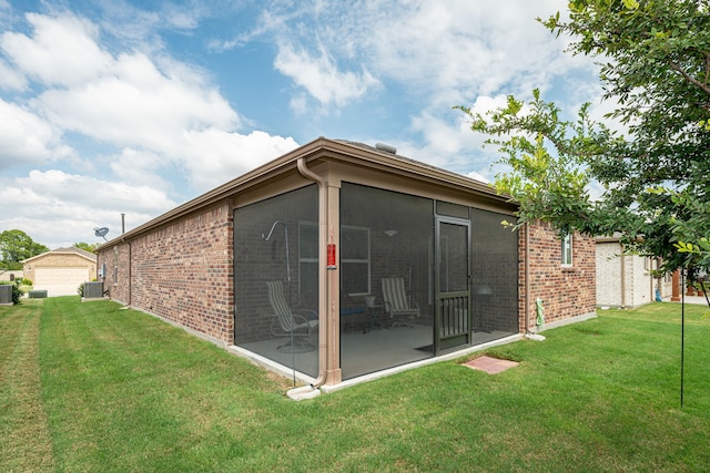 rear view of house with a garage, a lawn, an outbuilding, and central air condition unit