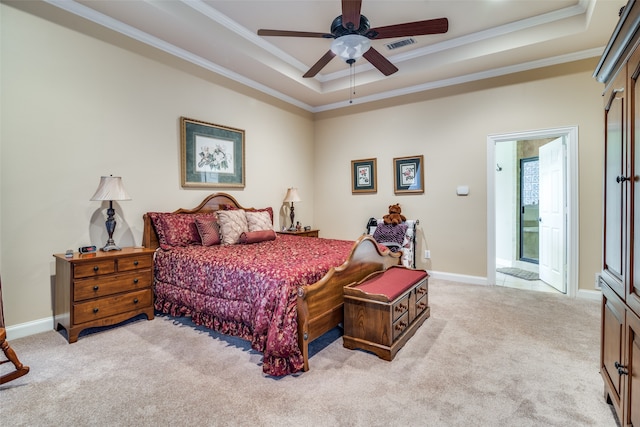 carpeted bedroom with crown molding, a raised ceiling, ensuite bathroom, and ceiling fan