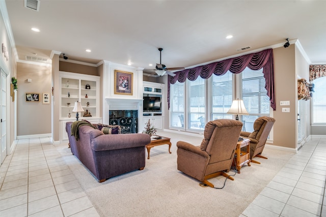 tiled living room featuring a healthy amount of sunlight, ceiling fan, and a tile fireplace