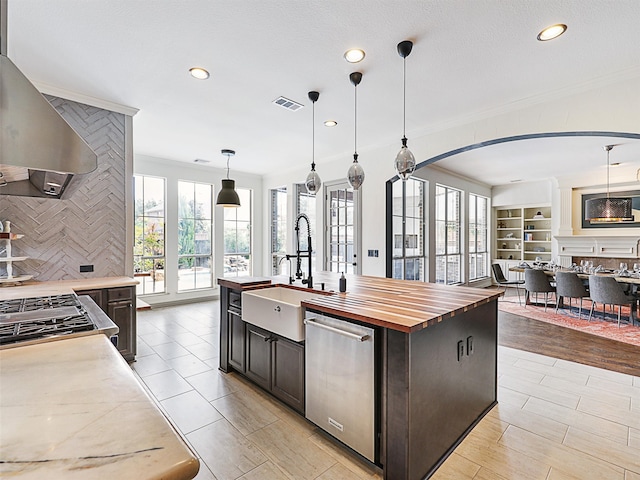 kitchen with light hardwood / wood-style flooring, wood counters, stainless steel appliances, sink, and a kitchen island with sink