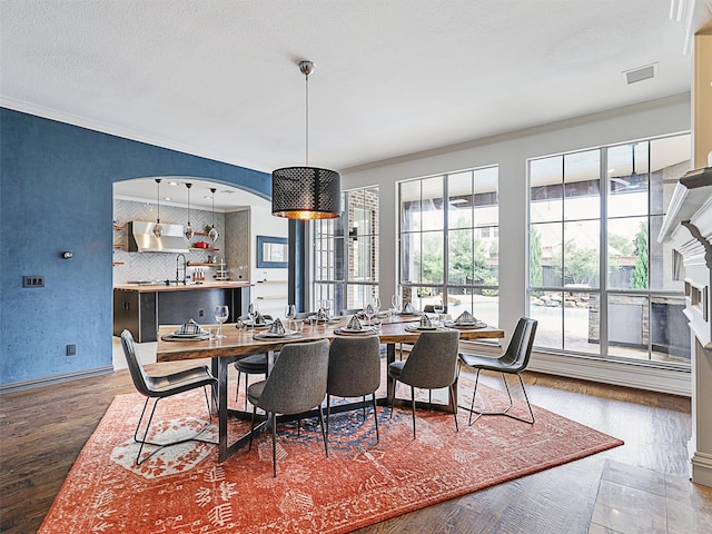 dining area with hardwood / wood-style floors, sink, a textured ceiling, and ornamental molding