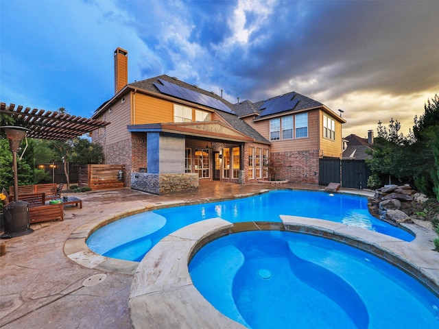 pool at dusk with an in ground hot tub, a pergola, and a patio