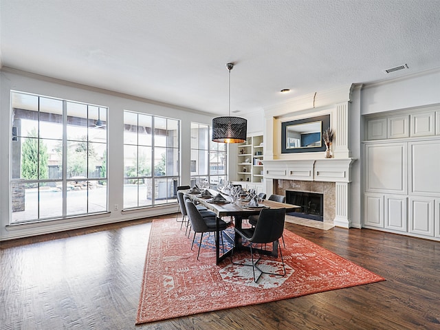 dining space featuring a fireplace, a textured ceiling, dark hardwood / wood-style floors, built in features, and ornamental molding